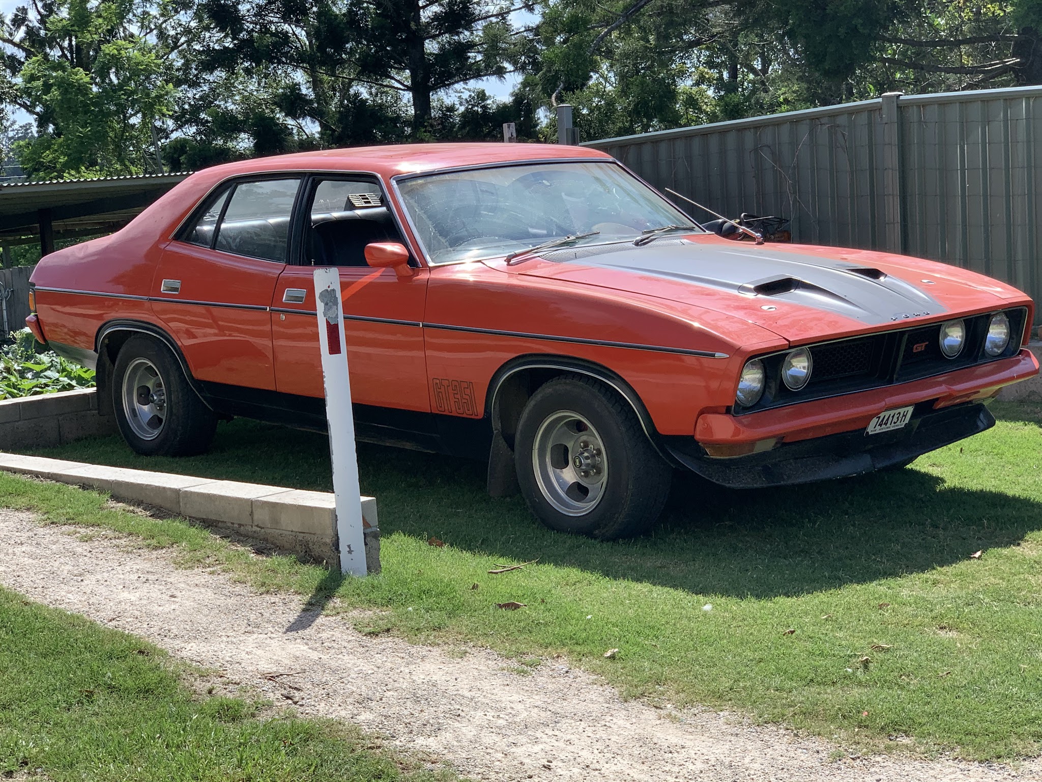 Red XB Falcon GT351 sedan with a grey bonnet stripe, parked on grass
