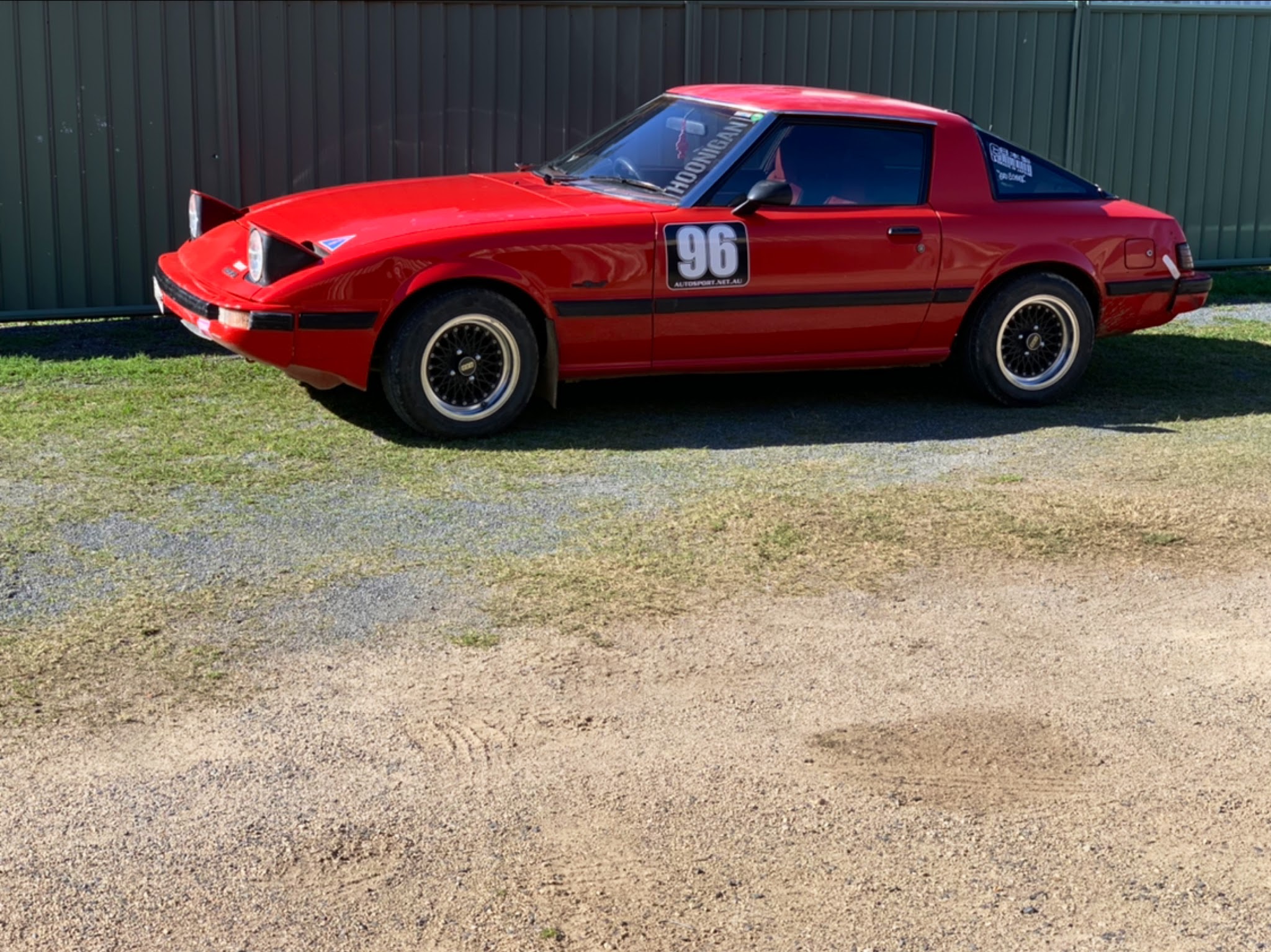 Red Mazda RX-7 with pop up headlights and a competition door roundel